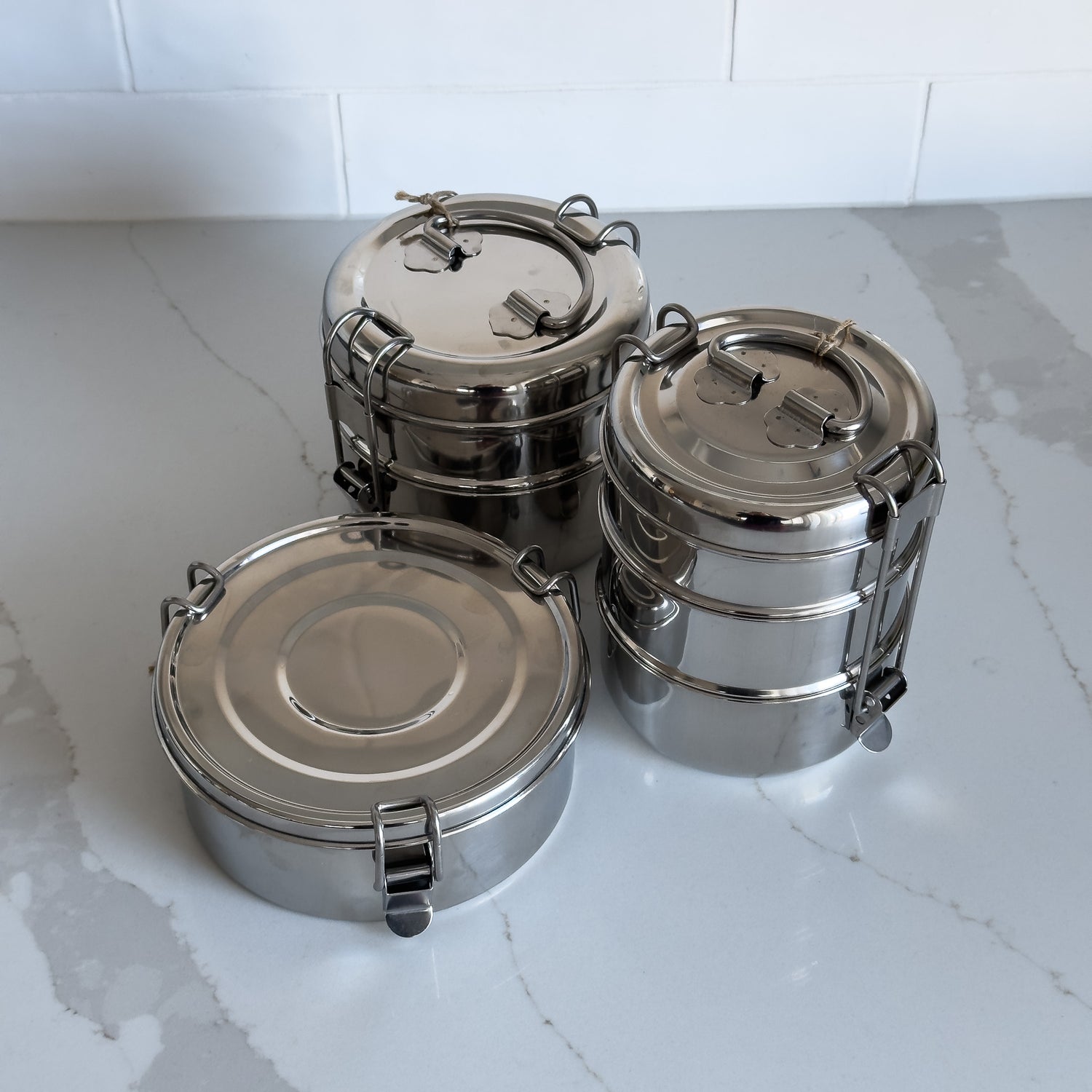 Three styles of sustainable stainless steel tiffin containers viewed from above