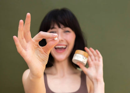 A person holds a TANIT toothpaste tab in front of their face