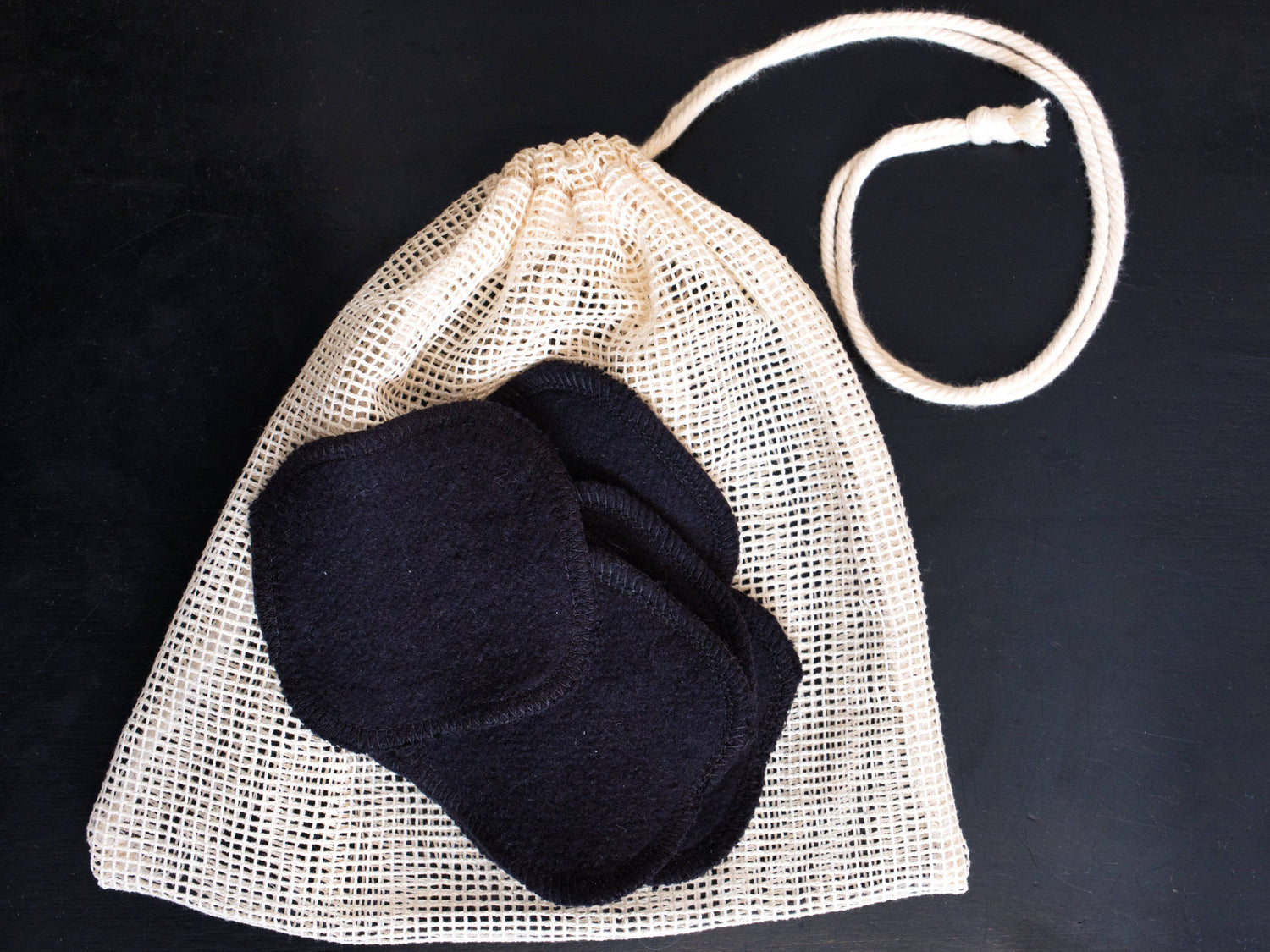 A small pile of washable hemp facial rounds with included cotton mesh washing bag